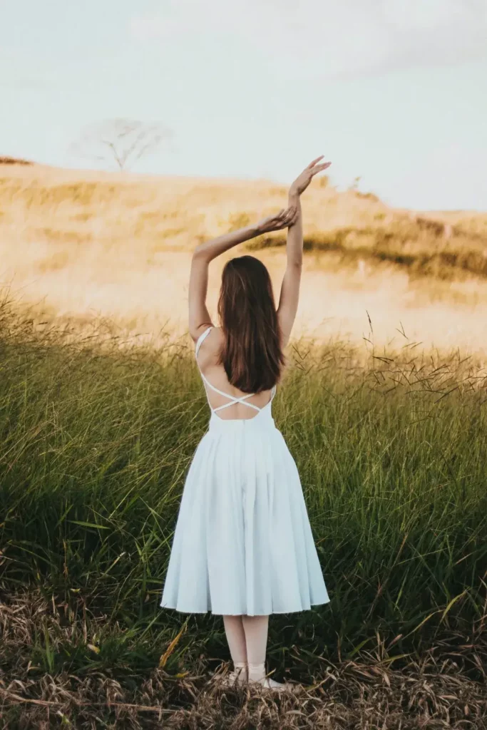 Femme en robe blanche dans un champ, confiance en soi et réconciliation avec son corps